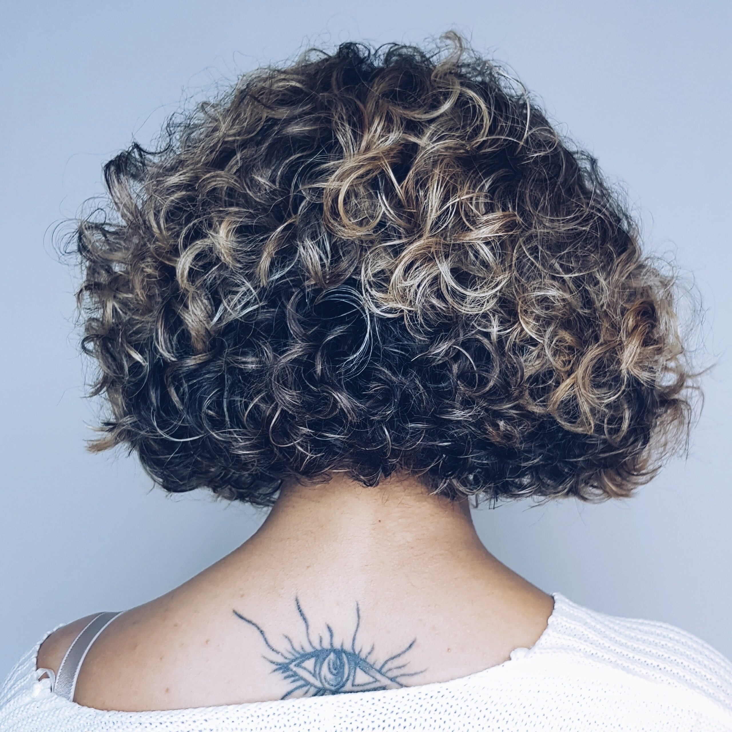 behind the head photo of curly hair with eye tattoo on back