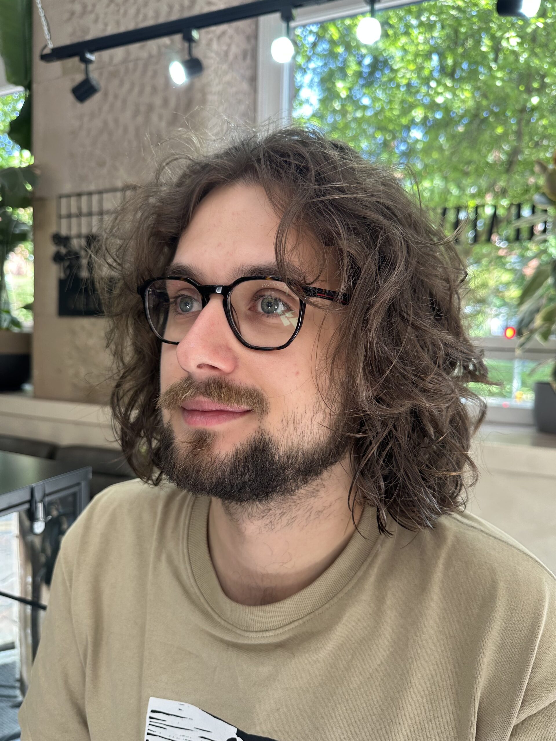 man-short-curly-hair a man wearing glasses facing slightly away from the camera with shoulder length curly hair