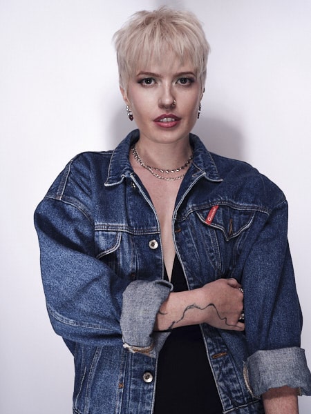 a woman in a denim jacket with short blonde hair