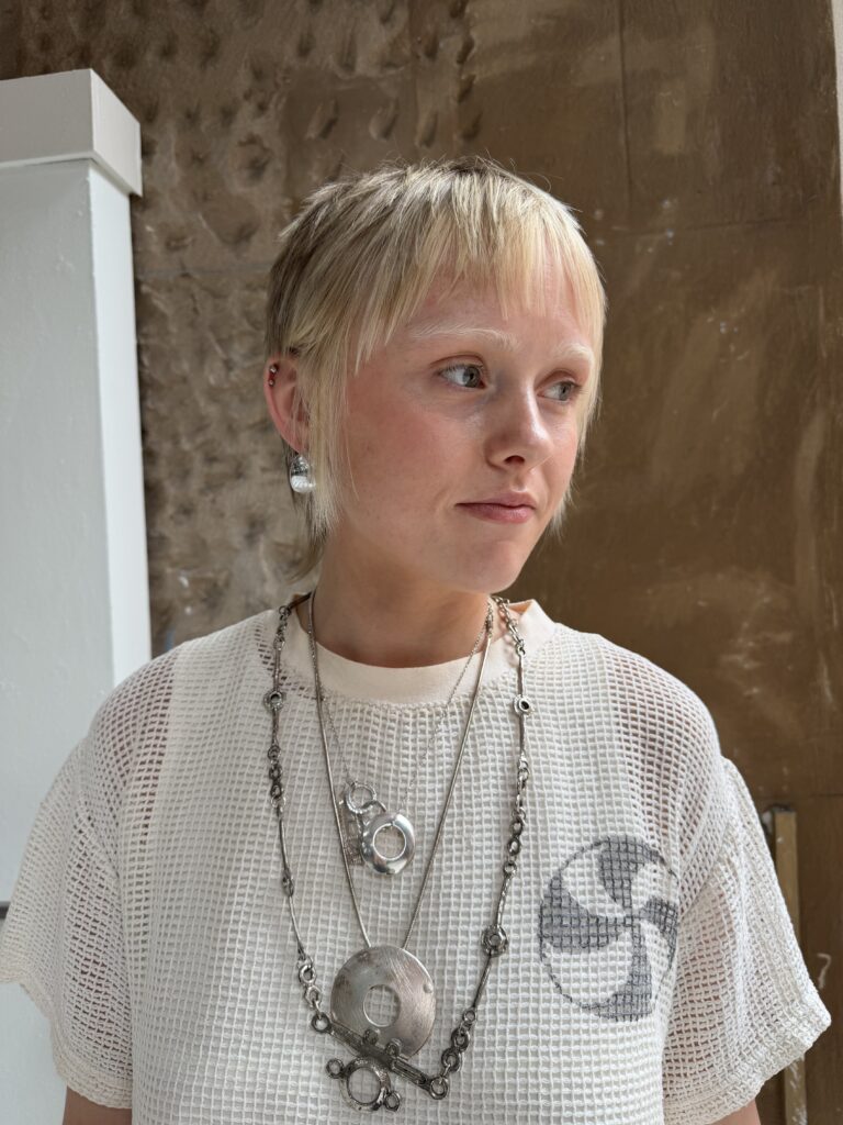 girl in white top with blonde hair and silver necklace